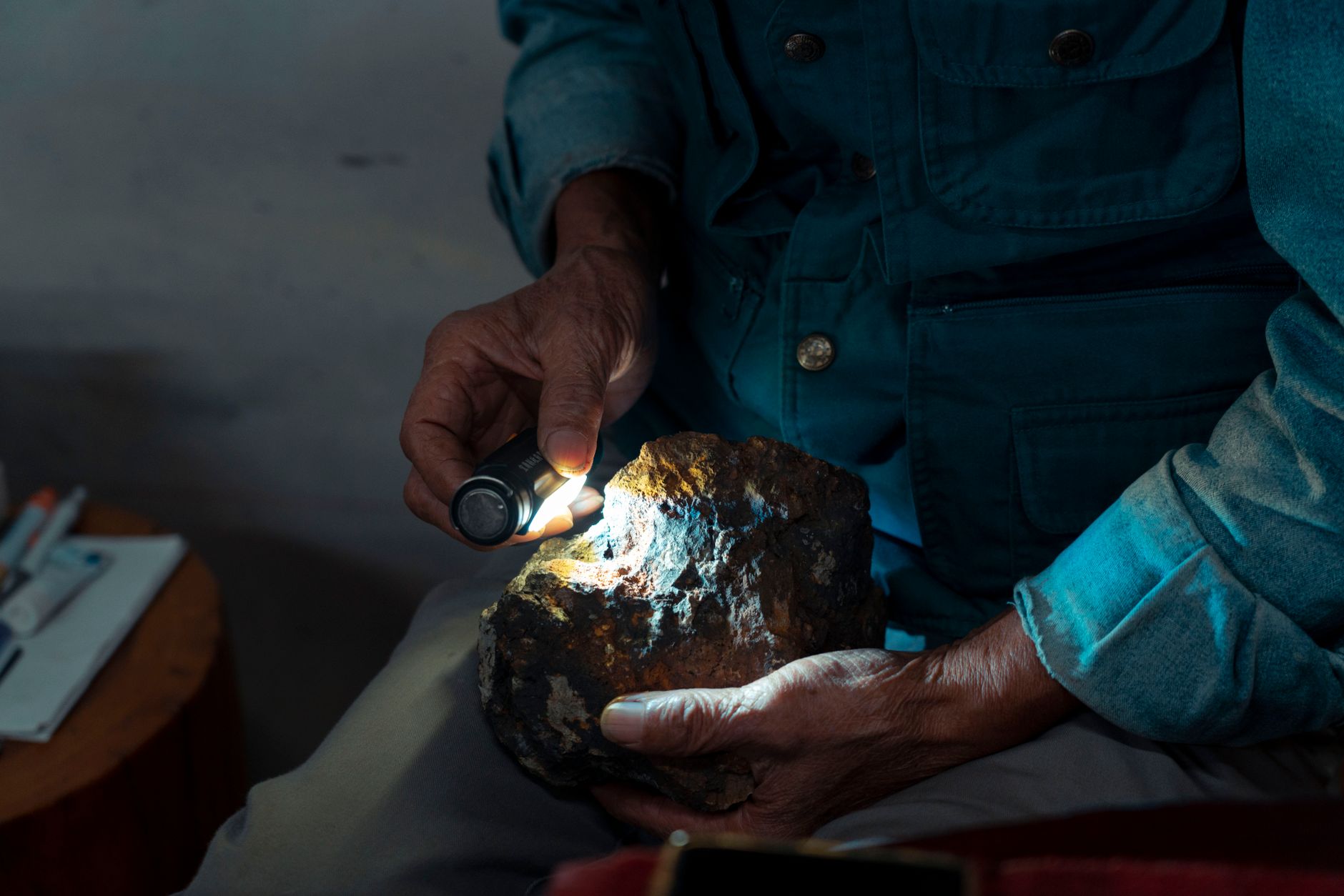 a hand holding a translucent agate against a bright flashlight revealing internal bands