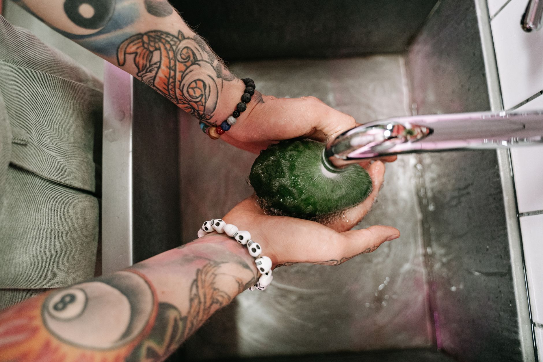 a person rinsing polished stones in a colander over a bucket
