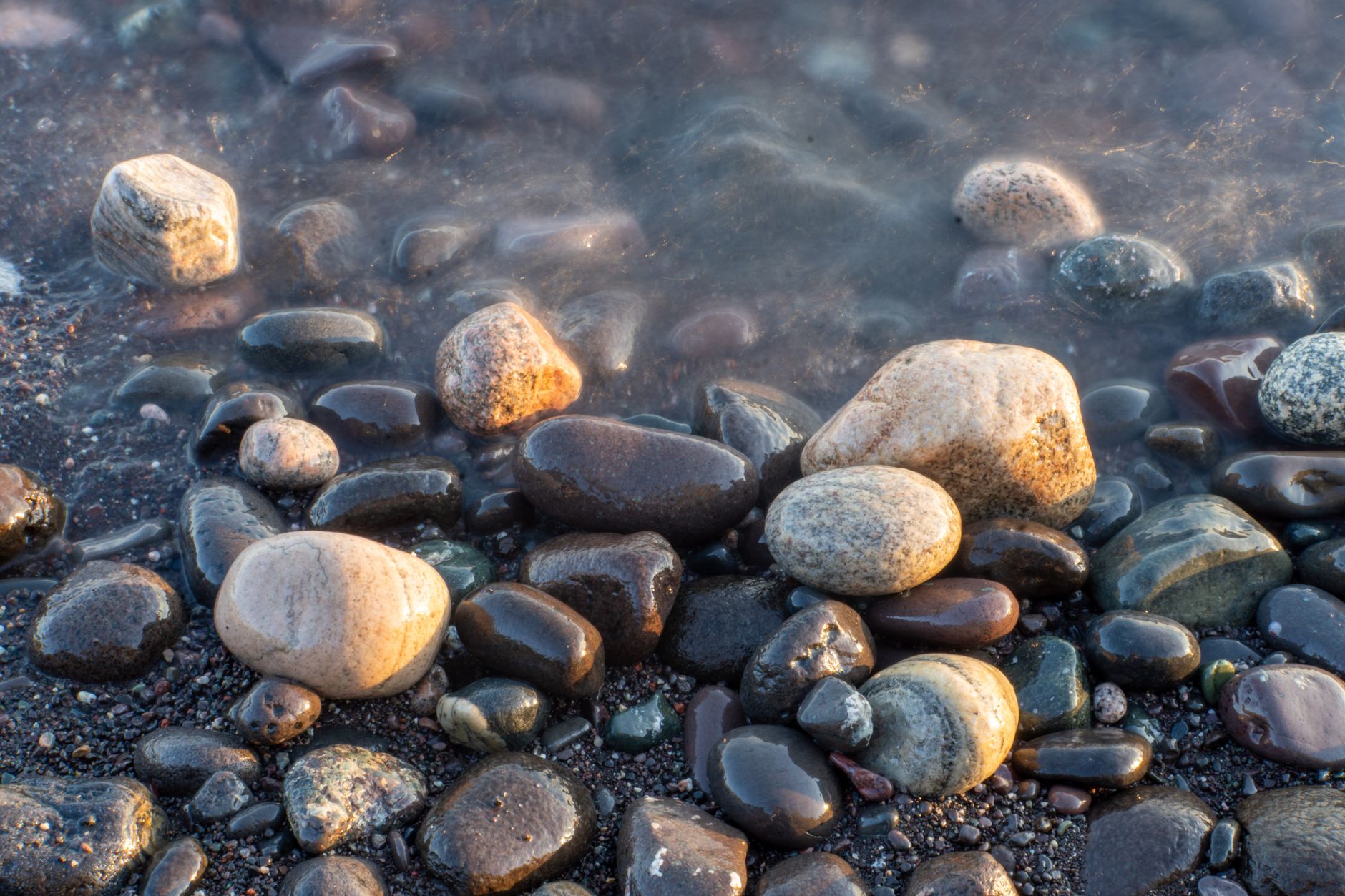 a wave-washed Lake Superior pebble beach with colorful agates exposed after ice melt
