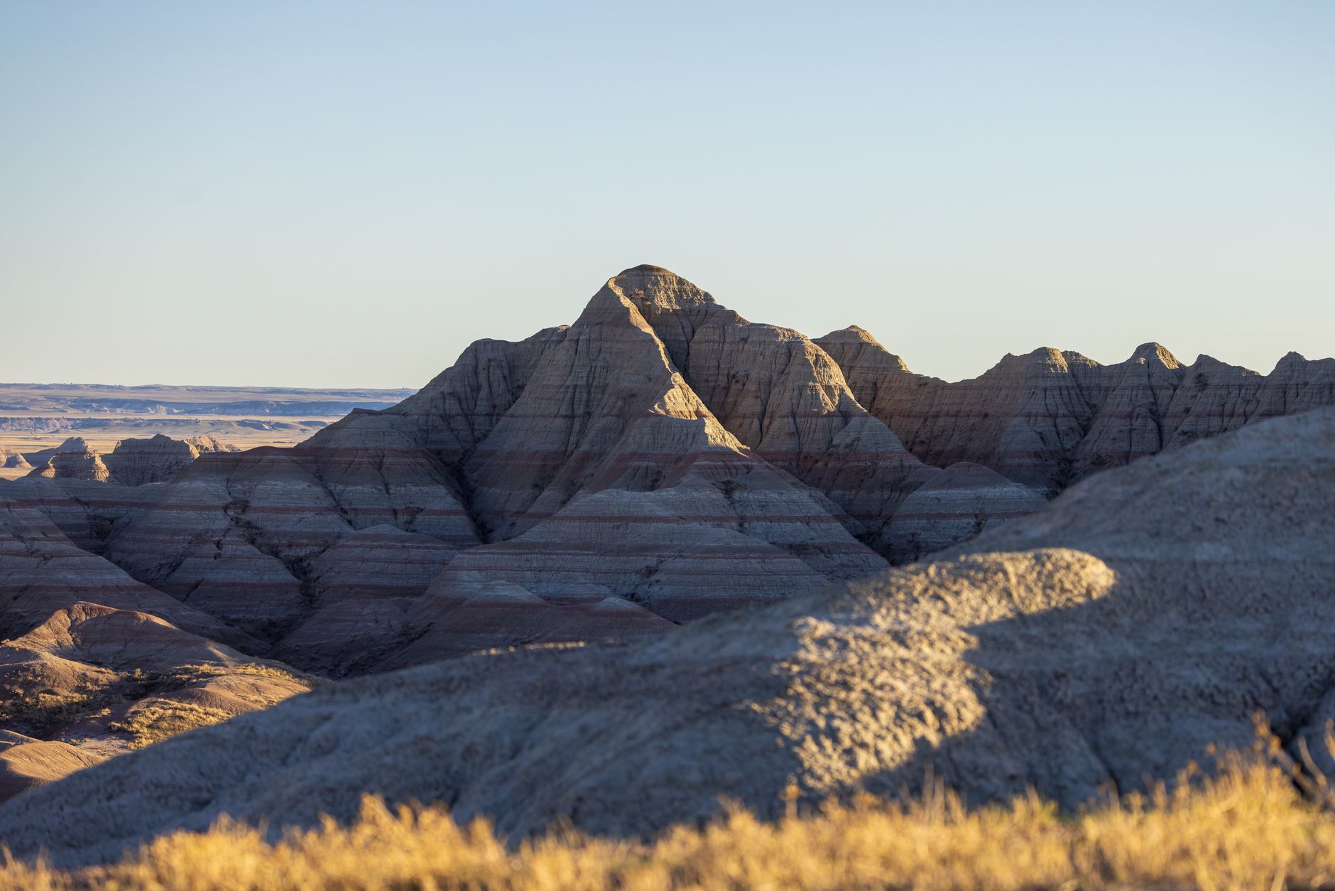 layered sedimentary rock formations in Badlands National Park under a blue sky
